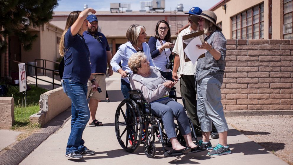 FILE - Michelle Lujan Grisham holds the wheelchair of her mother, Sonja Lujan, as they speak with voters after casting their ballots during the Democratic primary elections at Garfield Middle School in Albuquerque, N.M., on Tuesday, June 5, 2018. In 