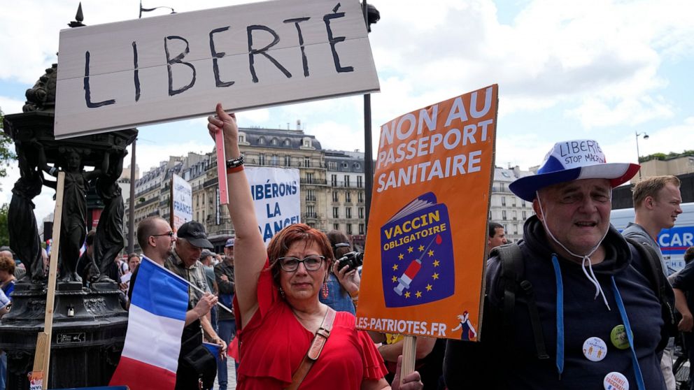 A protestor holds a sign which reads in French, "freedom" and "no to the Covid passport" as she attends a demonstration in Paris, France, Saturday, July 31, 2021. Demonstrators gathered in several cities in France on Saturday to protest against the C
