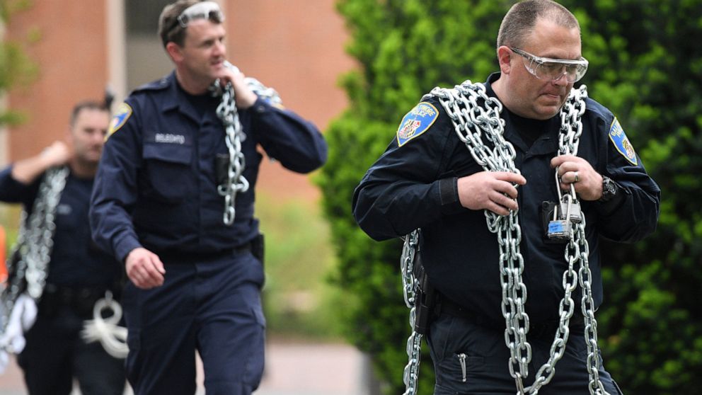 Baltimore Police carry chains that protesters had used during a monthlong sit-in at Garland Hall on Johns Hopkins' Homewood campus, Wednesday, May 8, 2019. Baltimore police arrested seven people as they ended a monthlong sit-in in the lobby of an adm
