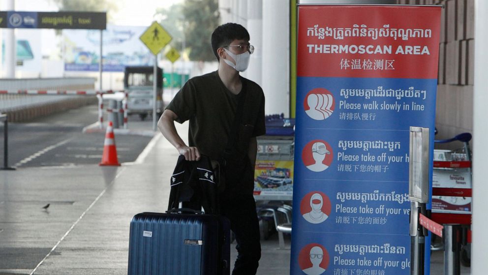 FILE - In this April 3, 2020, file photo, a tourist wearing a face mask enters an area of thermo scan at the quiet Phnom Penh International Airport in Phnom Penh, Cambodia. Cambodia's government announced plans Tuesday, Oct. 26, 2021 to reopen the co
