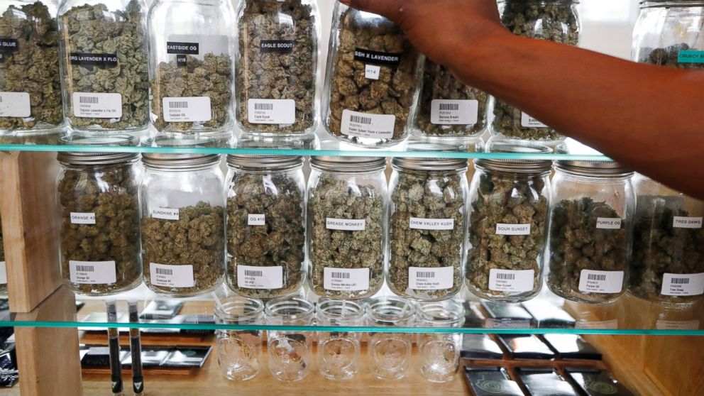 FILE - In this Oct. 2, 2018, file photo, a clerk reaches for a container of marijuana buds for a customer at Utopia Gardens, a medical marijuana dispensary in Detroit. Chronic pain is the most commonly cited reason people give when they enroll in sta