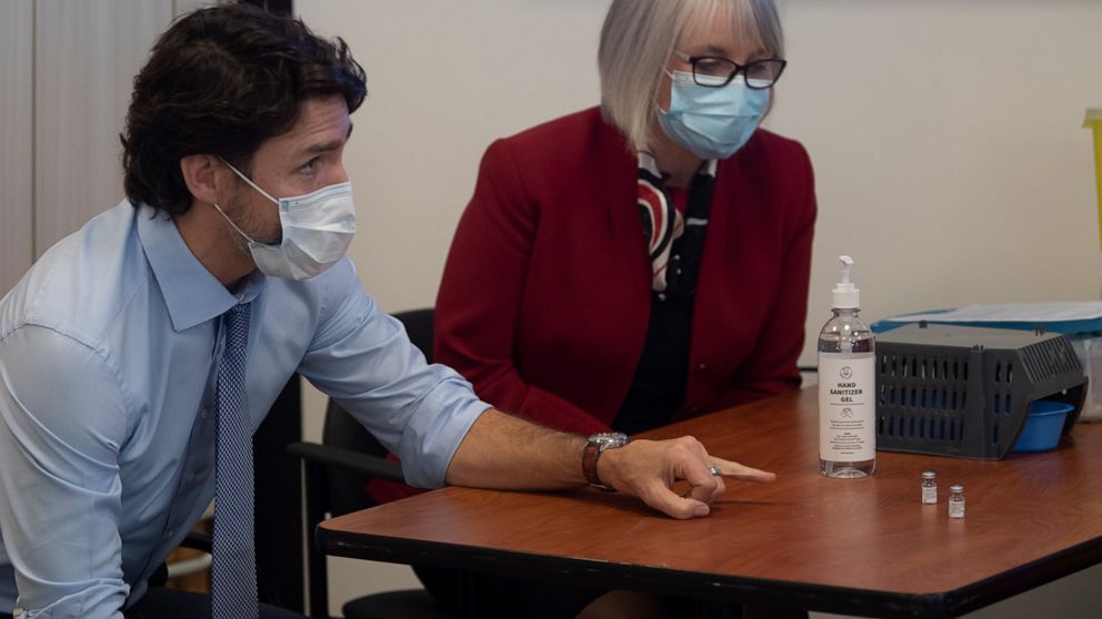 Canadian Prime Minister Justin Trudeau and Minister of Health Patty Hajdu look at empty vials which held the Pfizer-BioNTech COVID-19 vaccine during a visit to the Ottawa Hospital, Tuesday, Dec. 15, 2020 in Ottawa. (Adrian Wyld/The Canadian Press via AP)