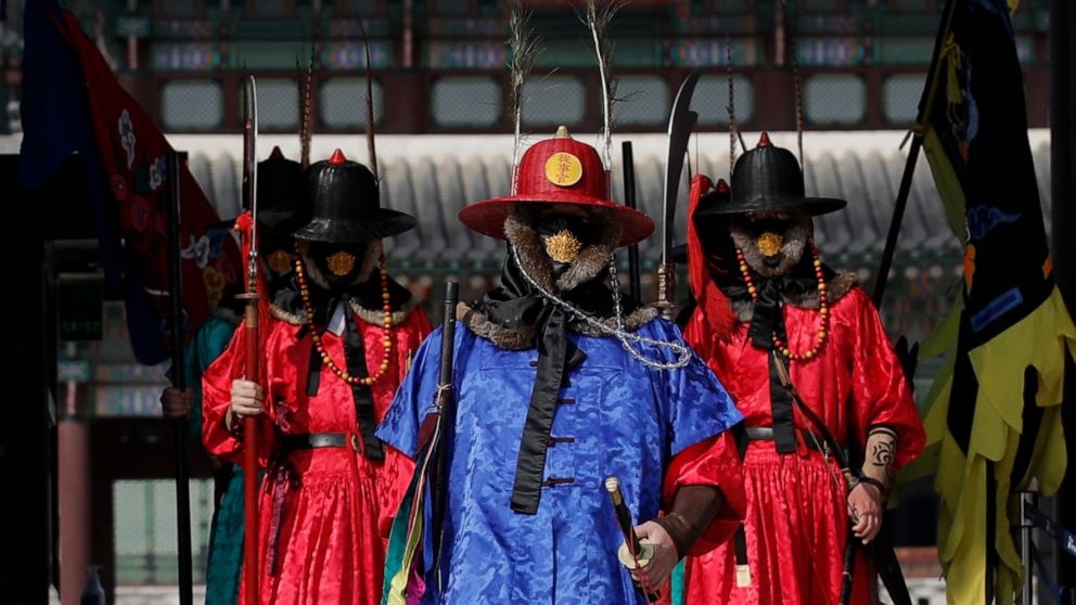 Officials wearing traditional guard uniforms and protective face masks walk at the Gyeongbok Palace, the main royal palace during the Joseon Dynasty and one of South Korea's well known landmarks in Seoul, South Korea, Saturday, Feb. 29, 2020. The cor