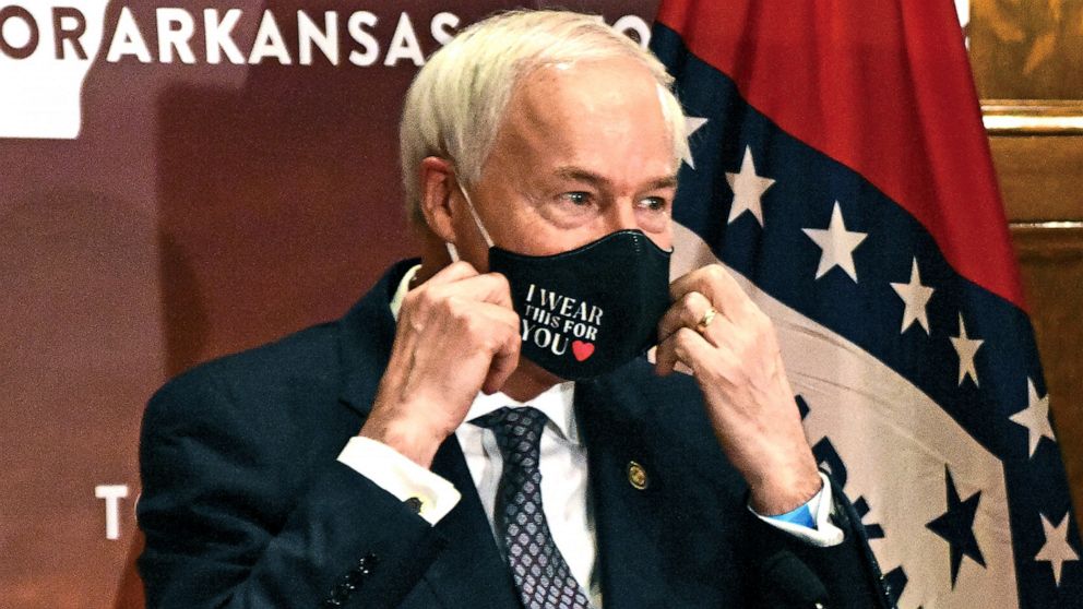 FILE - In this July 20, 2020 file photo, Arkansas Gov. Asa Hutchinson removes his mask before a briefing at the state capitol in Little Rock. Hutchinson has signed into law a measure that would allow doctors to refuse to treat someone because of mora