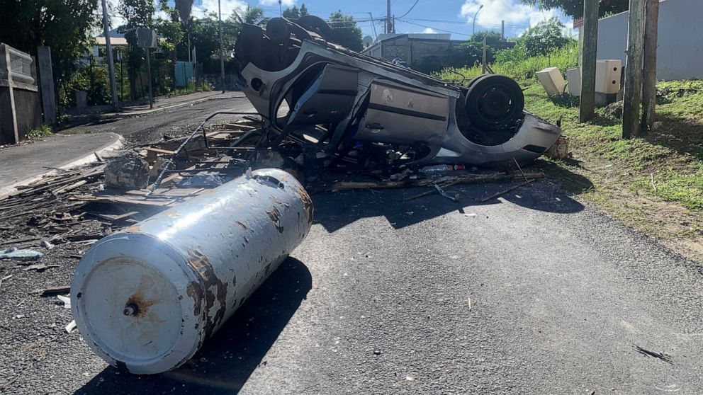An overturned car is pictured in a s street of Le Gosier, Guadeloupe island, Sunday, Nov.21, 2021. French authorities are sending police special forces to the Caribbean island of Guadeloupe, an overseas territory of France, as protests over COVID-19 