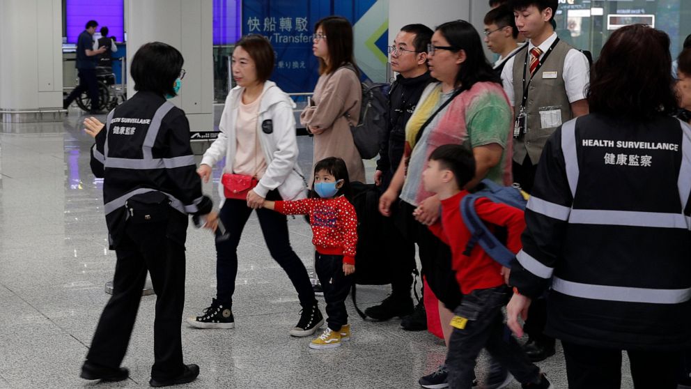 Health surveillance officer use device to check temperature of passengers before the immigration counters at International airport in Hong Kong, Saturday, Jan. 4, 2020. Hong Kong authorities activated a newly created "serious response" level Saturday