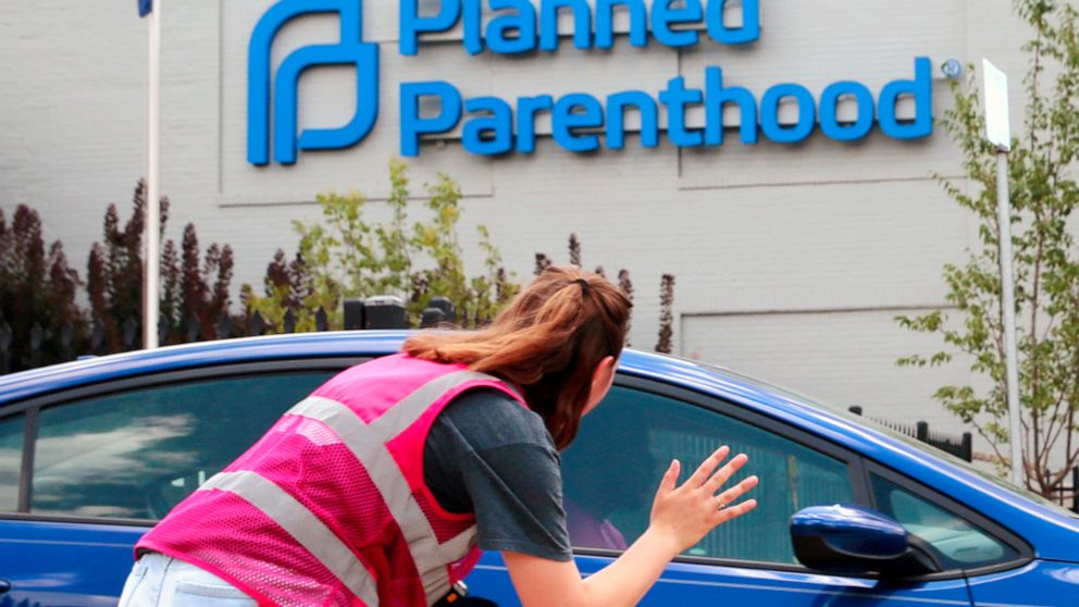 FILE - In this June 28, 2019 file photo, Ashlyn Myers of the Coalition for Life St. Louis, waves to a Planned Parenthood staff member in St. Louis, Mo. The Trump administration says its new regulation barring taxpayer-funded family planning clinics f