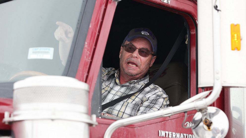 An angry American trucker speaks to people as they block highway 75 with heavy trucks and farm equipment and access to the Canada-United States border crossing at Emerson, Manitoba, Thursday, Feb. 10, 2022. The blockade was set up to rally against pr