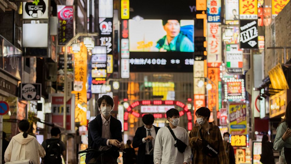 FILE - In this Oct. 1, 2021, file photo, people walk through the famed Kabukicho entertainment district of Tokyo on the first night of the government's lifting of a coronavirus state of emergency. Almost overnight, Japan has become a stunning, and so