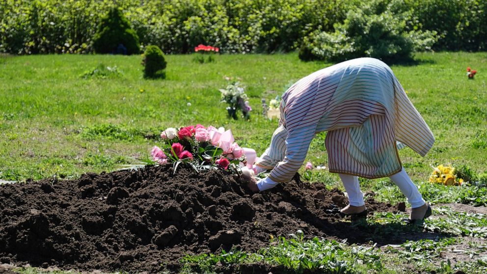 FILE - In this May 2, 2020, file photo, Erika Bermudez becomes emotional as she leans over the grave of her mother, Eudiana Smith, at Bayview Cemetery in Jersey City, N.J., Bermudez was not allowed to approach the gravesite until cemetery workers had