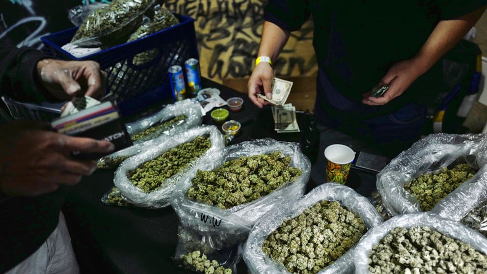 FILE - In this April 15, 2019, file photo, a vendor makes change for a marijuana customer at Rev-Up a cannabis marketplace in Los Angeles. An alliance of large cannabis businesses in the growing global marketplace has a message for the public: We're 