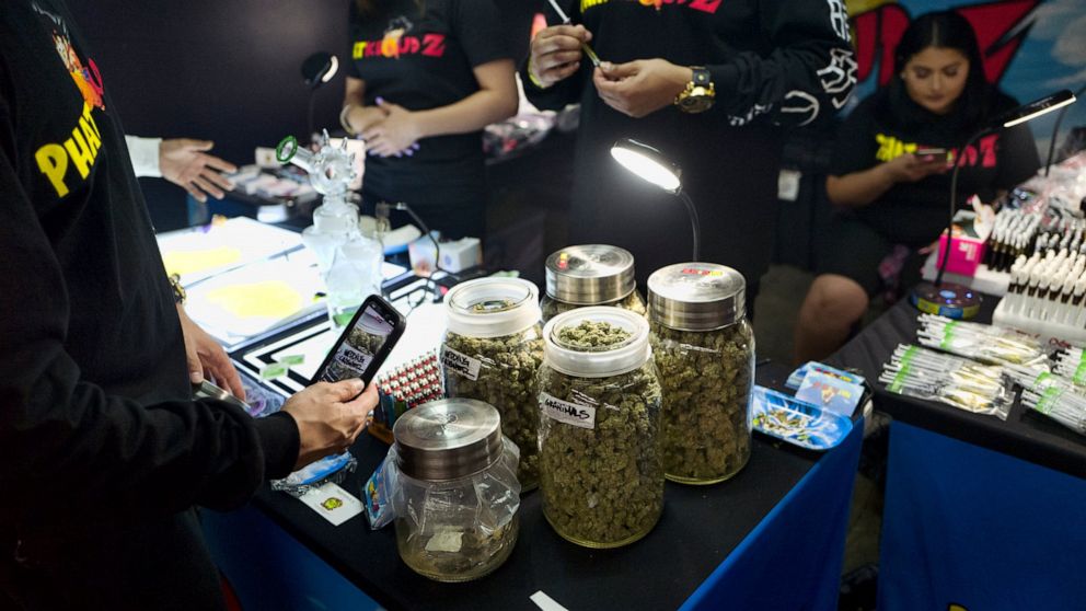 File - In this Friday, April 5, 2019, file photo, a customer takes a photo of large jars of marijuana from on display for sale at Rev-Up a cannabis marketplace in Los Angeles. California is trying a new strategy to cut into the state's huge illegal m