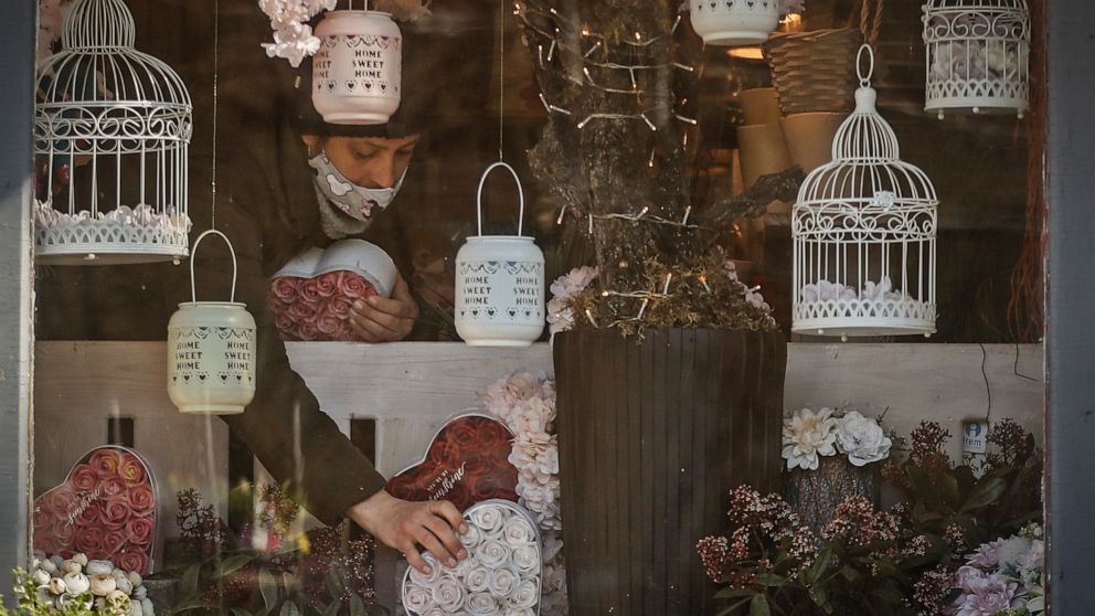A staff member of a flower shop sets up merchandise in the window in Budapest, Hungary, Wednesday April 7, 2021. Hungary's government lifted several lockdown restrictions on Wednesday, even as some doctors and medical experts urged caution after a re