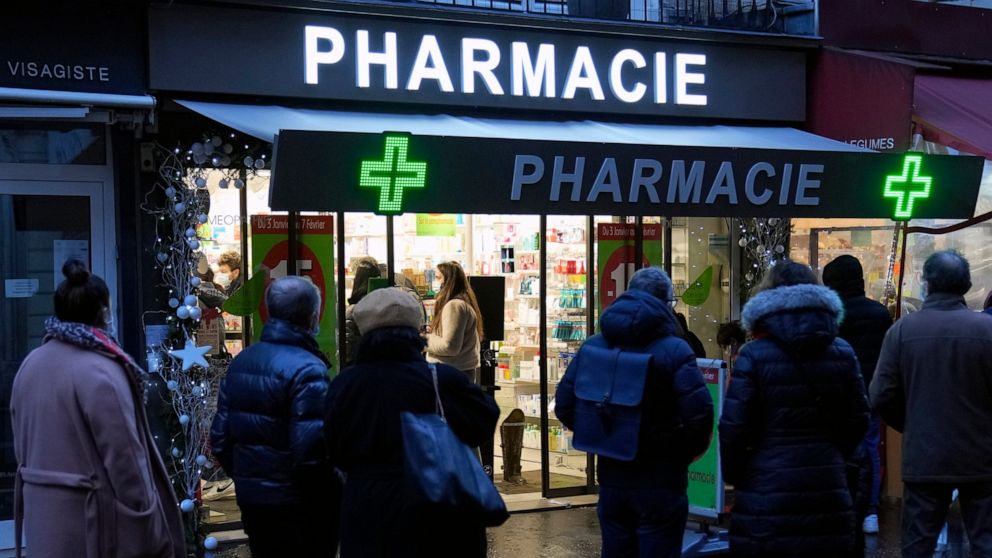 FILE - People wait in front of a pharmacy to get a COVID-19 test in Paris, France, Sunday, Jan. 9, 2022. On Friday, Dec. 9, 2022, President Emmanuel Macron announced France will make condoms free in pharmacies for anyone up to age 25 in the new year.