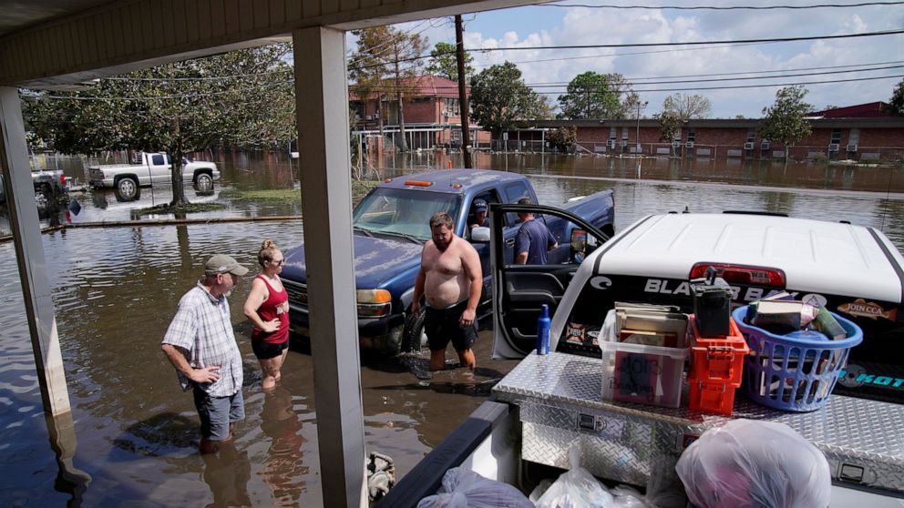 People stand in floodwaters while salvaging items from their flood-damaged home in the aftermath of Hurricane Ida, Wednesday, Sept. 1, 2021, in Jean Lafitte, La. Louisiana residents still reeling from flooding and damage caused by Hurricane Ida scram