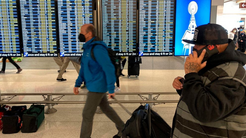 FILE - Travelers walk through Seattle-Tacoma International Airport on Friday, April 1, 2022 in Seattle. On Monday, April 18, 2022, a federal judge in Florida voided the national mask mandate covering airplanes and other public transportation saying i