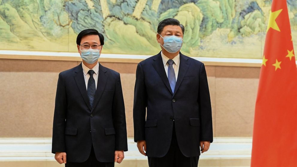 In this photo released by Xinhua News Agency, Chinese President Xi Jinping, right, and Hong Kong Chief Executive-elect John Lee pose for photo before their meeting in Beijing, Monday, May 30, 2022. Hong Kong's next leader, John Lee, has received an o