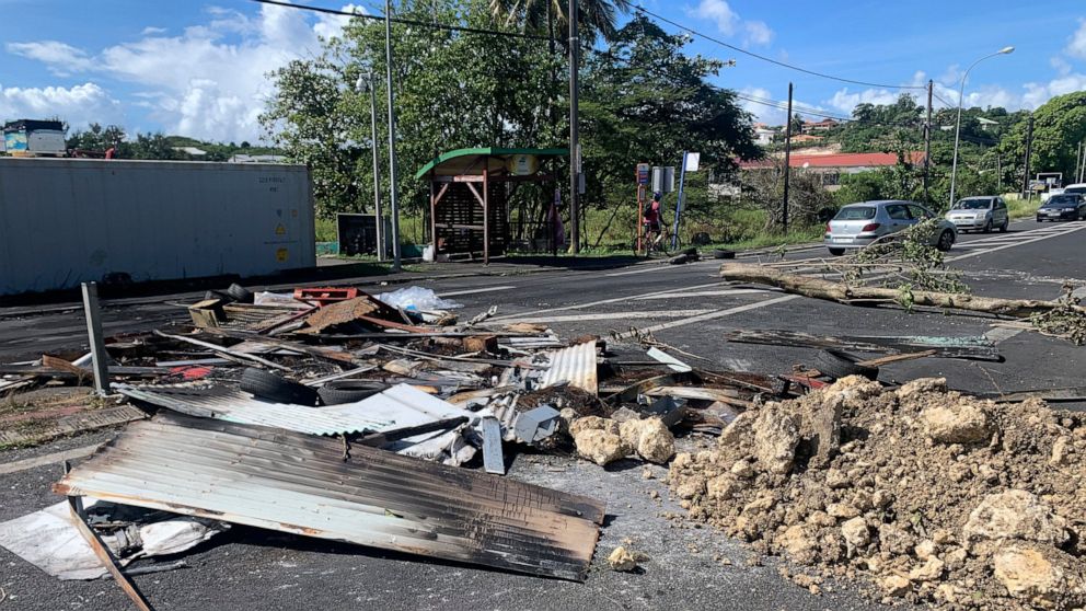 Debris left by demonstrators block a street of Le Gosier, Guadeloupe island, Sunday, Nov.21, 2021. French authorities sent police special forces to the Caribbean island of Guadeloupe, an overseas territory of France, as protests over COVID-19 restric