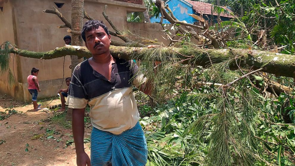 A villager clears tree branches fallen in front of his house after Cyclone Amphan hit the region, at Baguranjalpai village in East Midnapore district in West Bengal state, India, Friday, May 22, 2020. People forgot about social distancing and crammed