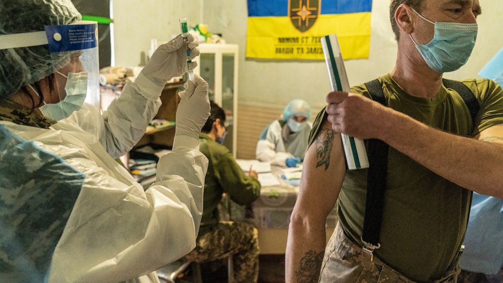 A Ukrainian serviceman prepares to receive a dose of the AstraZeneca COVID-19 vaccine marketed under the name CoviShield at a military base near the front-line town of Krasnohorivka, eastern Ukraine, Friday, March 5, 2021. The country designated 14,0