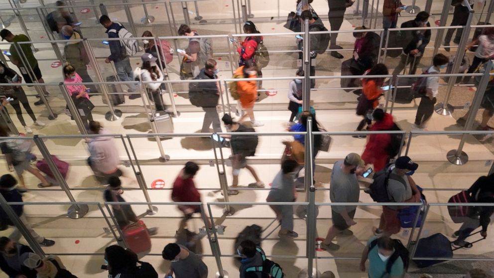 To prevent the spread of COVID-19, plexiglass keeps travelers separated as they make their way through the line to clear security at Love Field in Dallas, Friday, Dec. 31, 2021. (AP Photo/LM Otero)