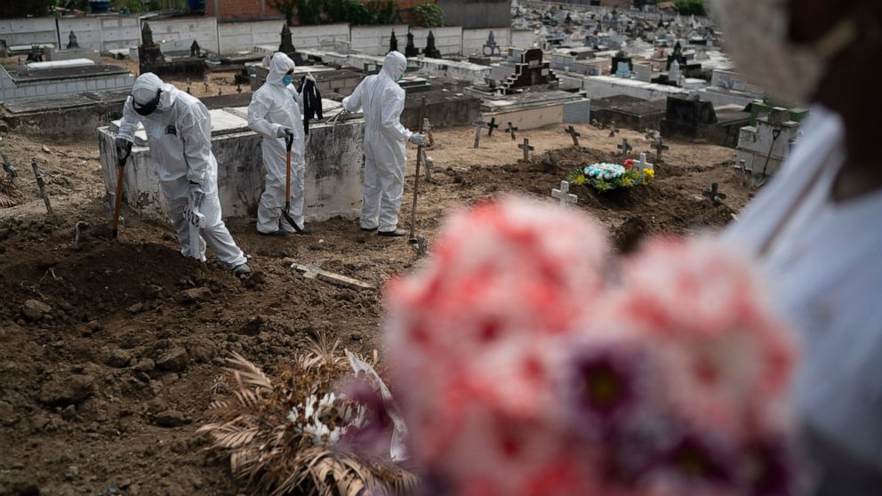Cemetery workers wearing hazmat suits complete the burial of Ana Maria, a 56-year-old nursing assistant who died from the new coronavirus, in Rio de Janeiro, Brazil, Tuesday, April 28, 2020. Ana Maria's daughter Taina dos Santos said that the situati