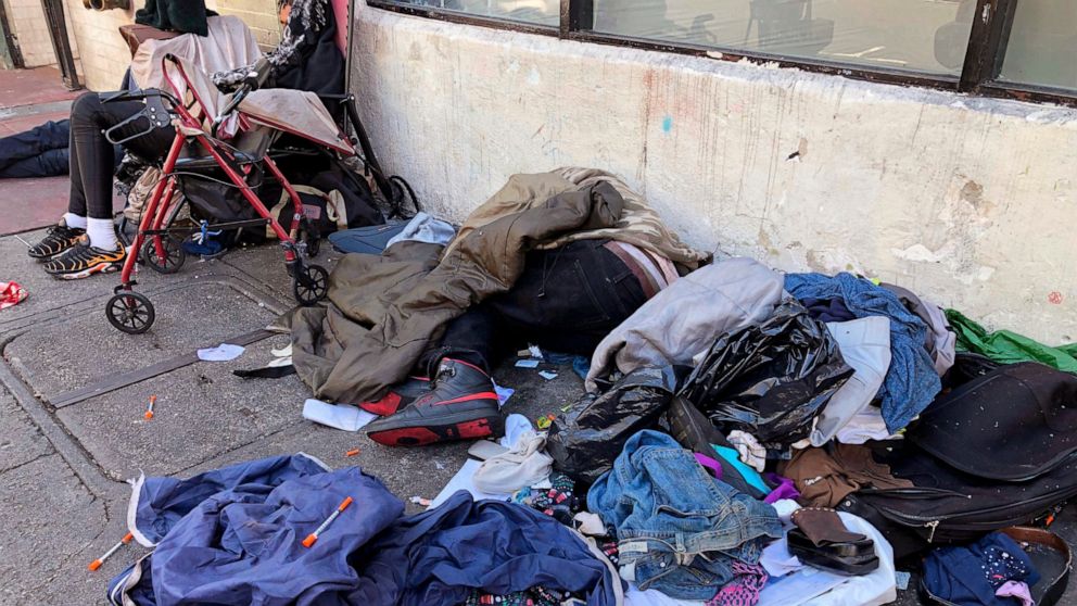 FILE - People sleep near discarded clothing and used needles on a street in the Tenderloin neighborhood in San Francisco, on July 25, 2019. The San Francisco Board of Supervisors will consider Thursday, Dec. 23, 2021, an emergency order to speed up t