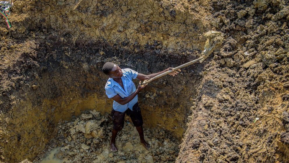 Mathias Okwako, who started as a gold miner since schools remained closed, works in his old school uniform at an open-cast gold mining site in the village of Mawero, on the outskirts of Busia town, in eastern Uganda on Tuesday, Oct. 19, 2021. With sc