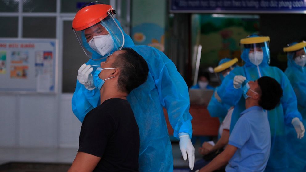 Medical workers take swab samples from people in Vung Tau city, Vietnam Saturday, Aug. 21, 2021. Vietnam's government said it is sending troops to Ho Chi Minh city to help deliver food and aid to households as it further tightens restrictions on peop