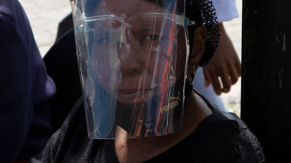A woman wears a face shield to protect against COVID-19 at a taxi rank in Soweto, South Africa, Tuesday, April 5, 2022. South Africa is seeing a rapid surge of COVID-19 cases from a sub-variant of omicron, say health experts. (AP Photo/Denis Farrell)