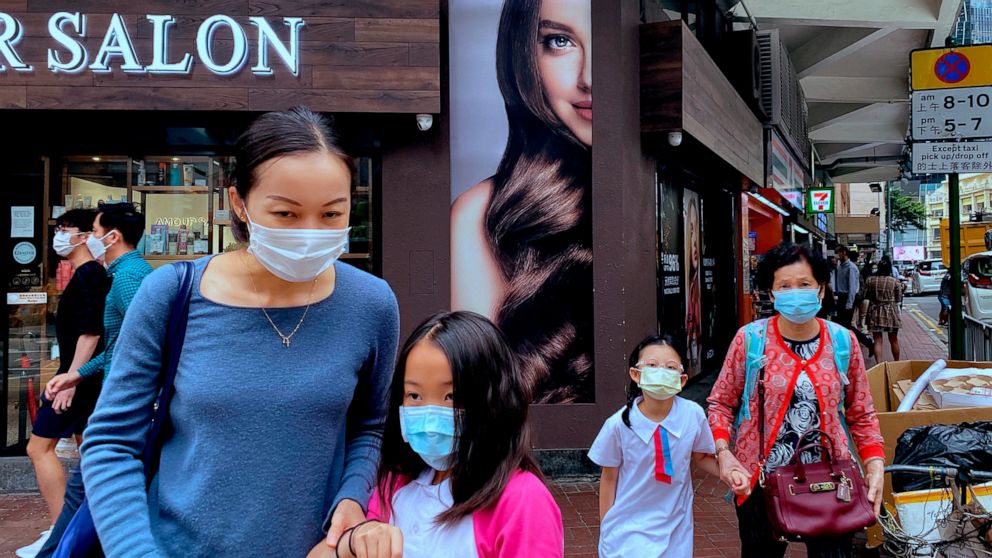 People wearing face masks to help protect against the spread of the coronavirus walk at a street in Hong Kong, Monday, April 26, 2021. Hong Kong and Singapore said Monday they would launch an air travel bubble in May, months after an initial arrangem