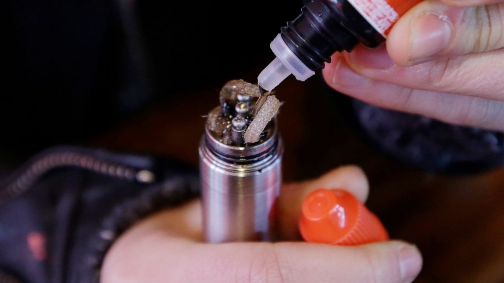 FILE - In this Feb. 20, 2014 file photo, a liquid nicotine solution is poured into a vaping device at a store in New York. In September 2019, U.S. health officials are investigating what might be causing hundreds of serious breathing illnesses in peo
