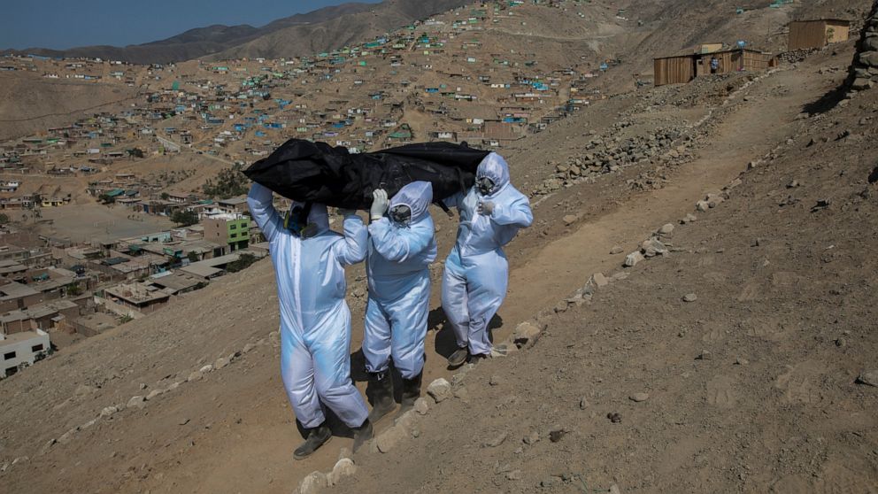 Venezuelans Luis Zerpa, from left, Luis Brito and Jhoan Faneite, carry a body bag that contains the remains of 51-year-old Marcos Espinoza who is suspected to have died of the new coronavirus, down a steep hill to a waiting hearse in a working-class 