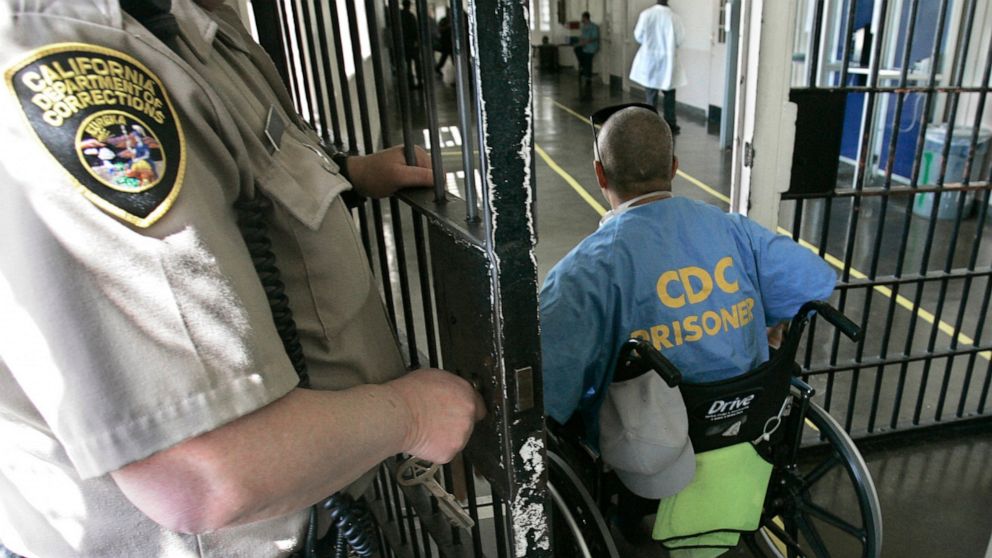 FILE - A wheelchair-bound inmate wheels himself through a checkpoint at the California Medical Facility in Vacaville, Calif., on April 9, 2008. California corrections officials have begun limiting medical parole only to inmates so ill they are on ven