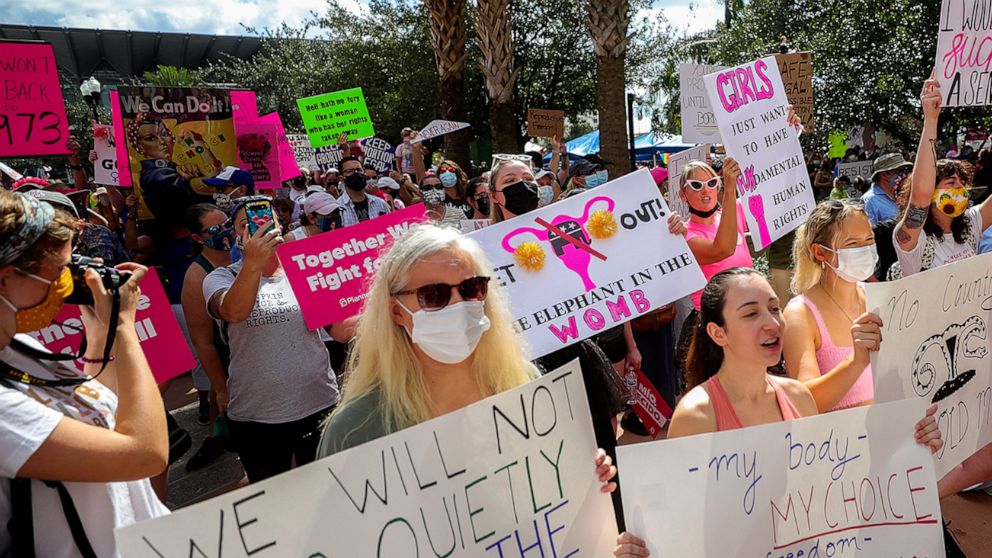 FILE - Participants wave signs as they walk back to Orlando City Hall during the March for Abortion Access on Saturday, Oct. 2, 2021, in Orlando, Fla. Abortions after 15 weeks would be banned in Florida under a proposal Republican senators have given