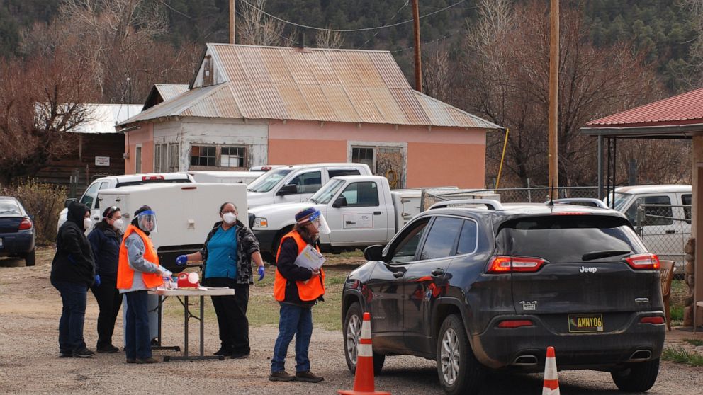 FILE - In this April 20, 2021, file photo medical workers and volunteers administer the coronavirus vaccine at a drive-thru immunization clinic at an inn and RV park in Mora, N.M. New Mexico is the latest U.S. state to offer cash lottery prizes in a 