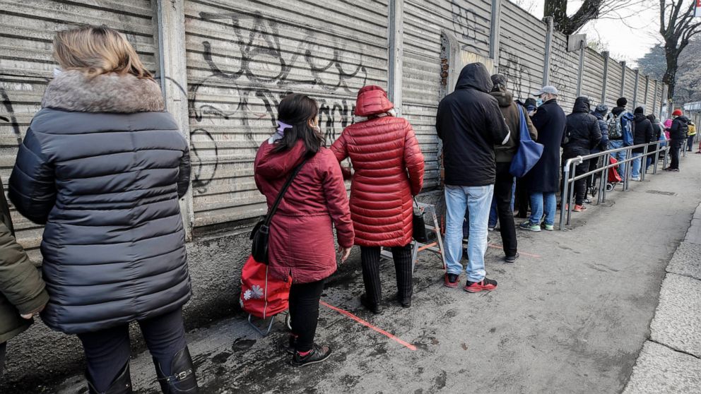 People queue for food at the 'Pane Quotidiano' (Daily Bread) Onlus, in Milan, northern Italy, Thursday, Dec. 17, 2020. Nowhere in Italy is poverty more evident than in Lombardy, the northern region that has been the pandemic epicenter in both surges.