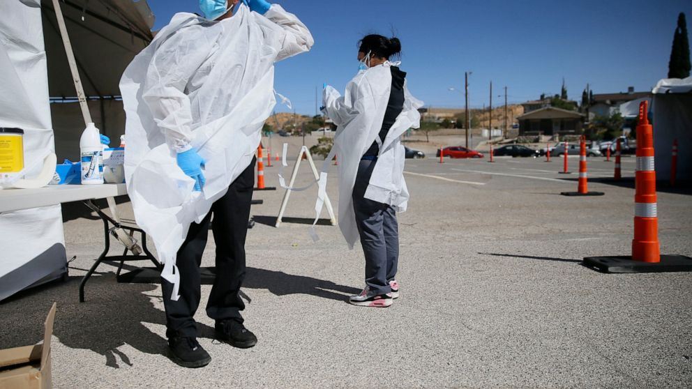 FILE - In this Oct. 26, 2020, file photo, Jacob Newberry puts on new PPE at the COVID-19 state drive-thru testing location at UTEP in El Paso, Texas. As the coronavirus pandemic surges across the nation and infections and hospitalizations rise, medic