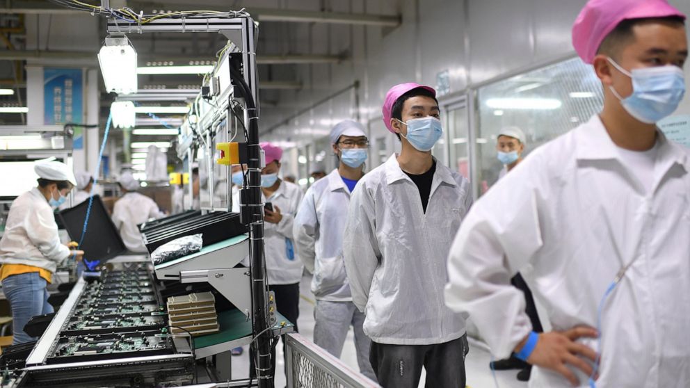 FILE - Workers line up to get tested for COVID-19 at the Foxconn factory in Wuhan in central China's Hubei province on Aug. 5, 2021. Employees at the world's biggest Apple iPhone factory have been beaten and detained in protests over contract dispute