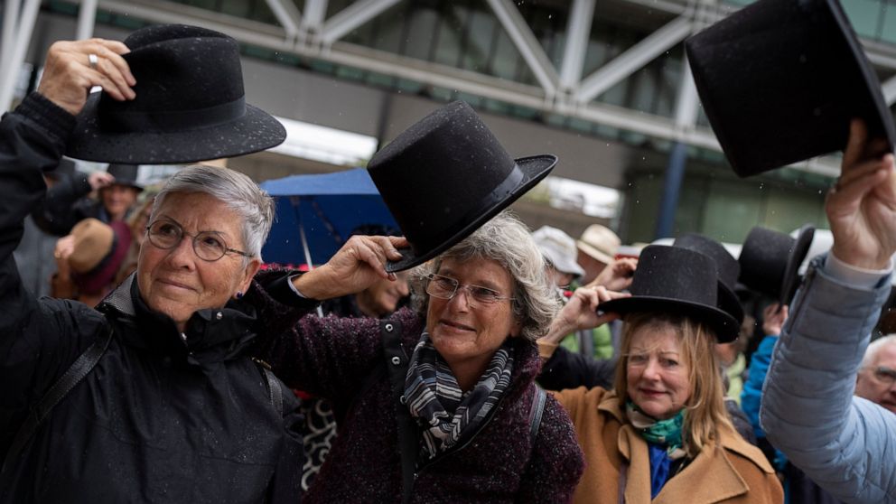 Campaigners take their hat off in a show of respect for people who took their own lives in The Hague, Netherlands, Monday, Oct. 10, 2022, where they calling for the decriminalization of assisted suicide in the Netherlands took the Dutch state to cour
