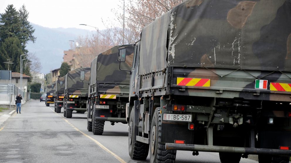 FILE - In this March 26, 2020 file photo, military trucks moving coffins of deceased people leave the cemetery of Bergamo, one of the areas worst hit by the coronavirus infection, on their way to a crematory in some other location as the local cremat