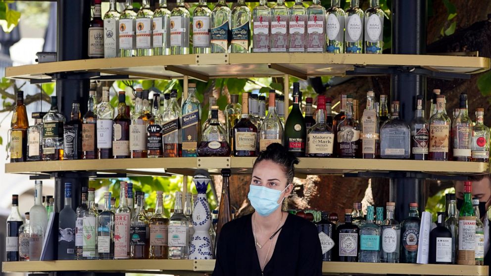 FILE - In this May 20, 2021, file photo, a bartender wears a mask while working at an outdoor bar amid the COVID-19 pandemic, at The Grove in Los Angeles. California workplace regulators are considering Thursday, June 3, 2021, whether to end mask rul