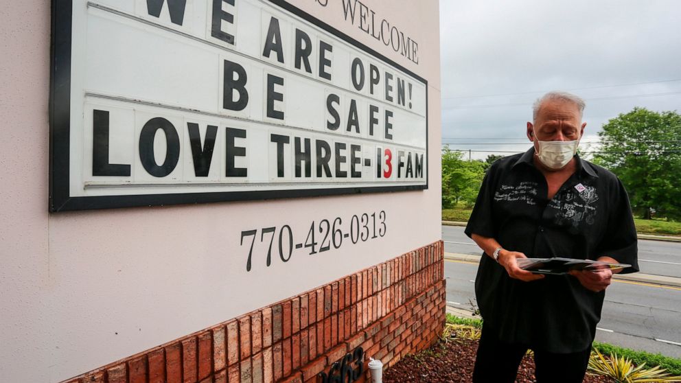 Lester Crowell, managing partner of Three-13 Salon, Spa & Boutique, changes the letters of the salon's sign on Friday, April 24, 2020, in Marietta, Ga. Barber shops, nail salons, gyms and a few other businesses reopened in Georgia on Friday as the Re