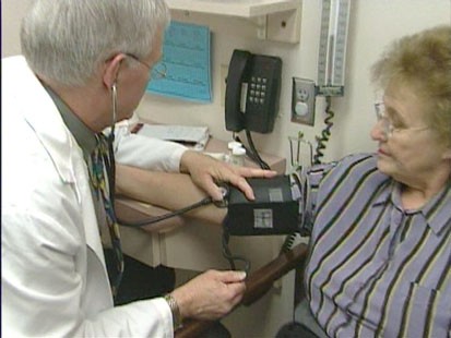 A doctor testing a womans blood pressure.