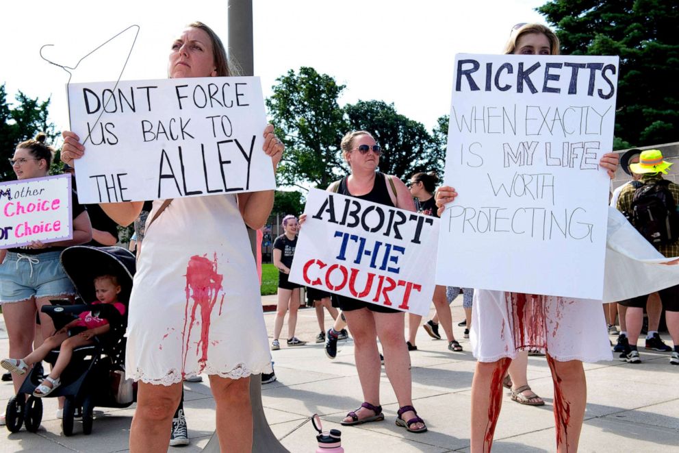 PHOTO: People wear red paint stained dresses while protesting the recent Supreme Court decision during a Abortion Rights Rally held in front of the Nebraska State Capitol on July 4, 2022, in Lincoln, Neb.