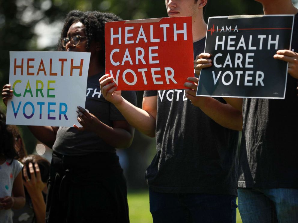 PHOTO: Demonstrators hold signs as Democratic leaders speak with reporters outside the U.S. Capitol on June 26, 2018 in Washington, D.C.