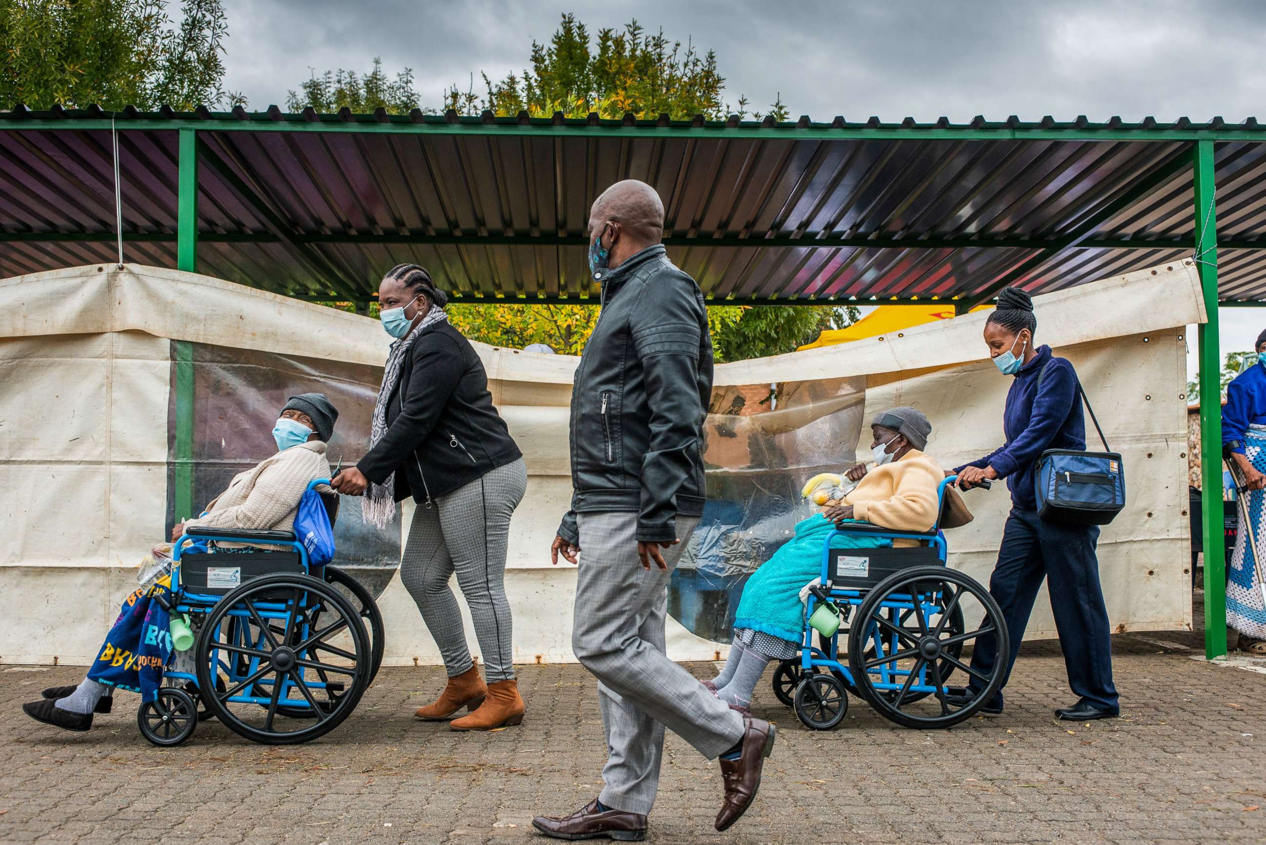 PHOTO: Elderly residents in wheelchairs are escorted to register for the COVID-19 vaccination program outside the Bonang Community Health Centre, in Brits, South Africa, April 30, 2021.