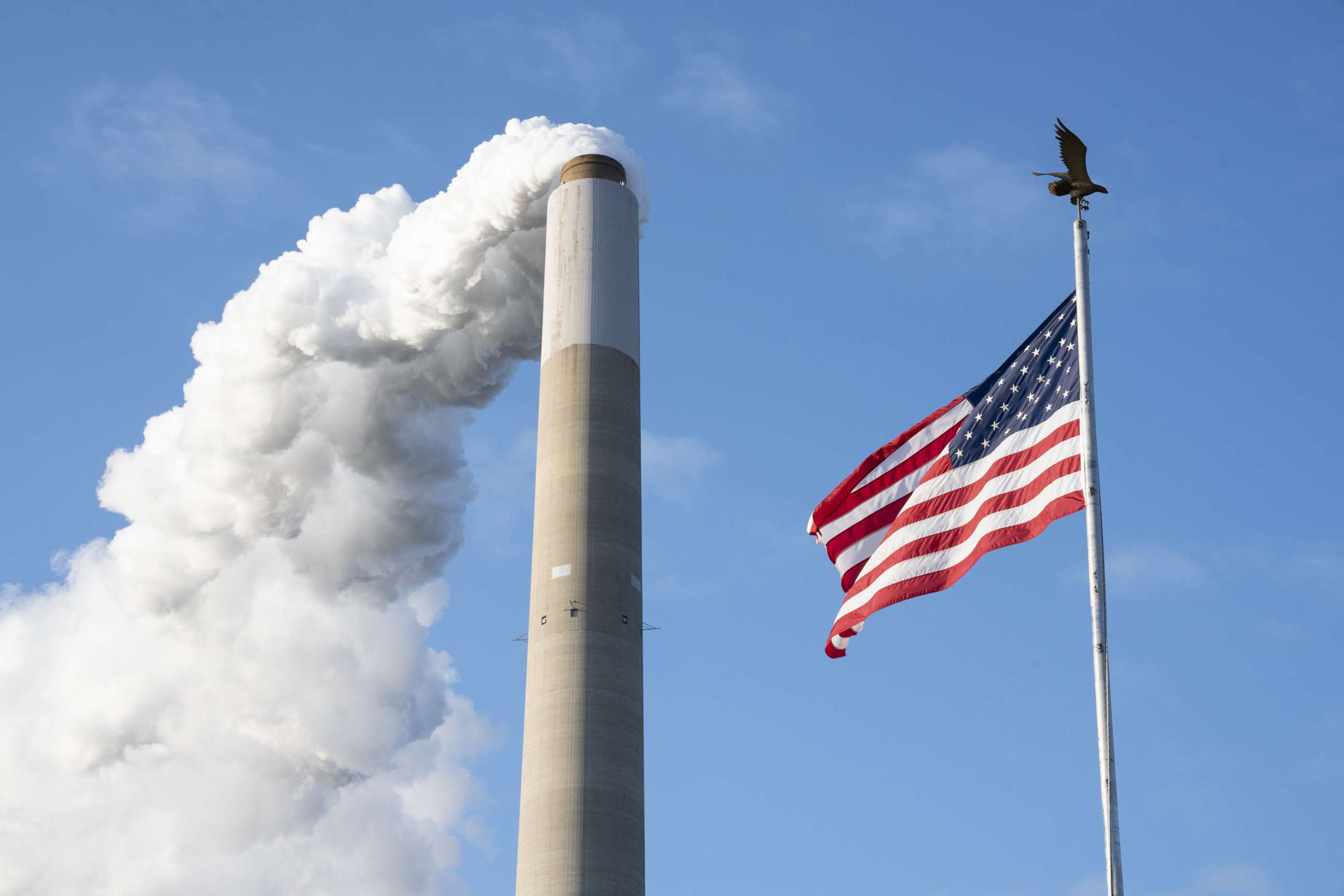 PHOTO: An American flag flies as emissions rise from a smoke stack at the Conesville Power Plant in Conesville, Ohio, April 18, 2020. 