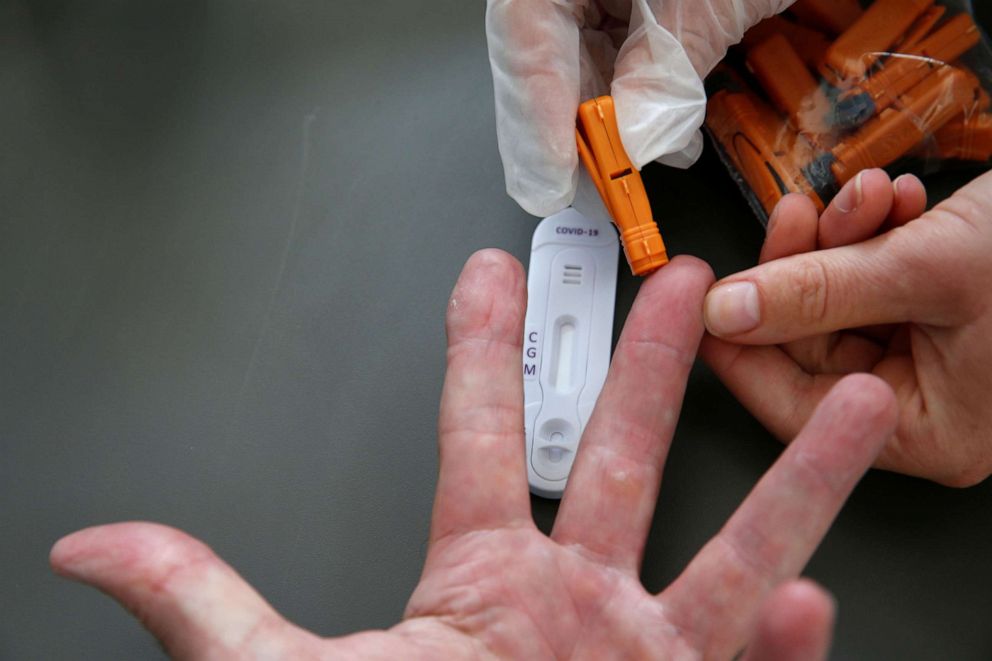 PHOTO: A pharmacist takes a blood sample for an antibody rapid diagnostic test for COVID-19 at a pharmacy in Cambrai, France, July 17, 2020.