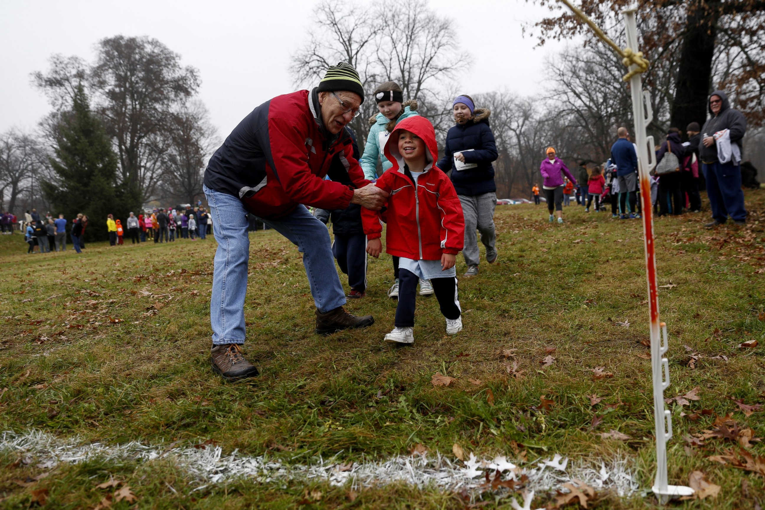 PHOTO: From left, Jim Loria, of Swartz Creek, helps Gabriel Riley, 4, of Burton, to the finish line during the 60th annual Thanksgiving Day Turkey Trot on Thursday, Nov. 24, 2016, at Mott Park in Flint, Mich.